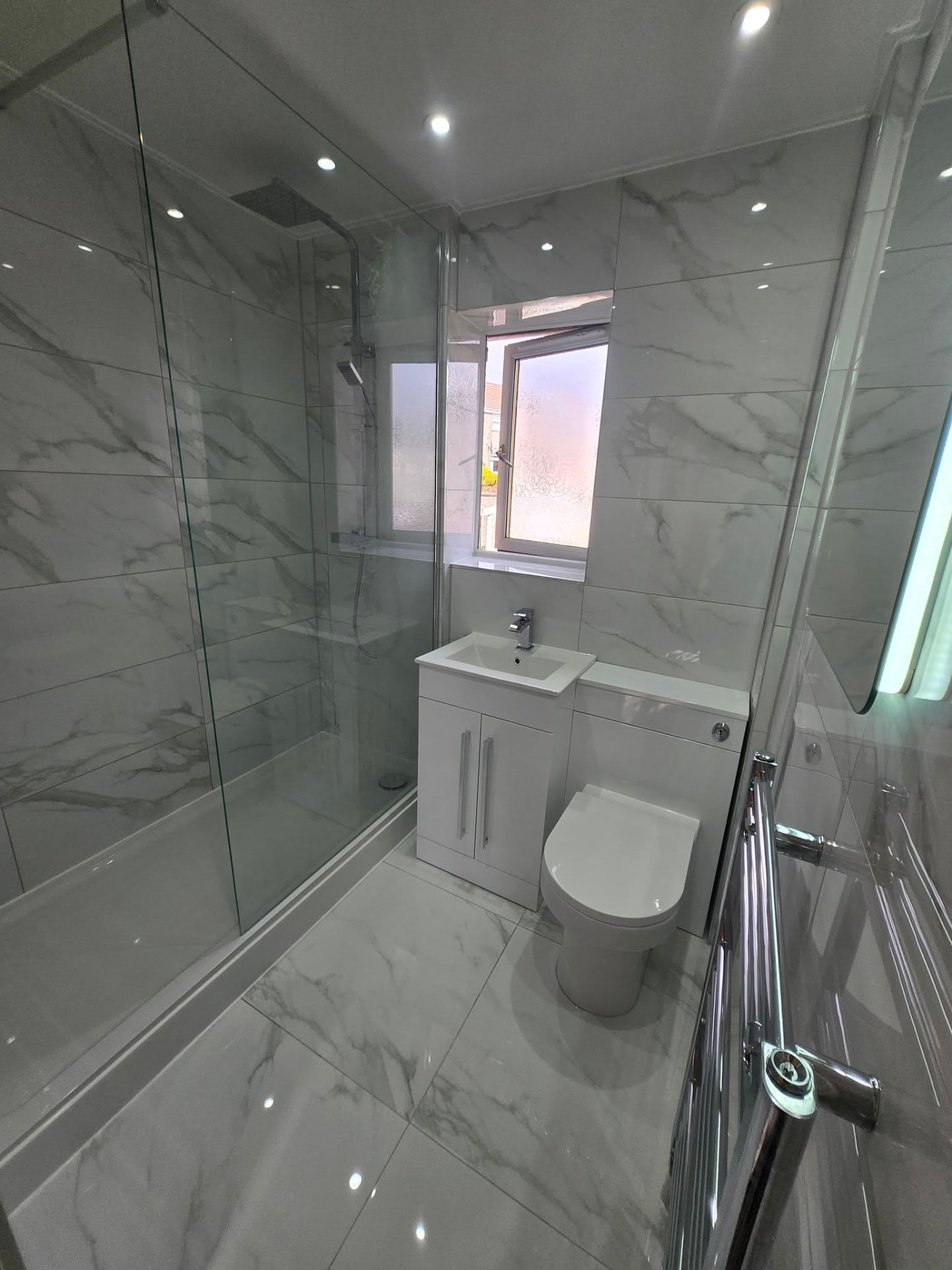 Marble-tiled shower room with glass walk-in shower, vanity and back-to-wall WC after refit
