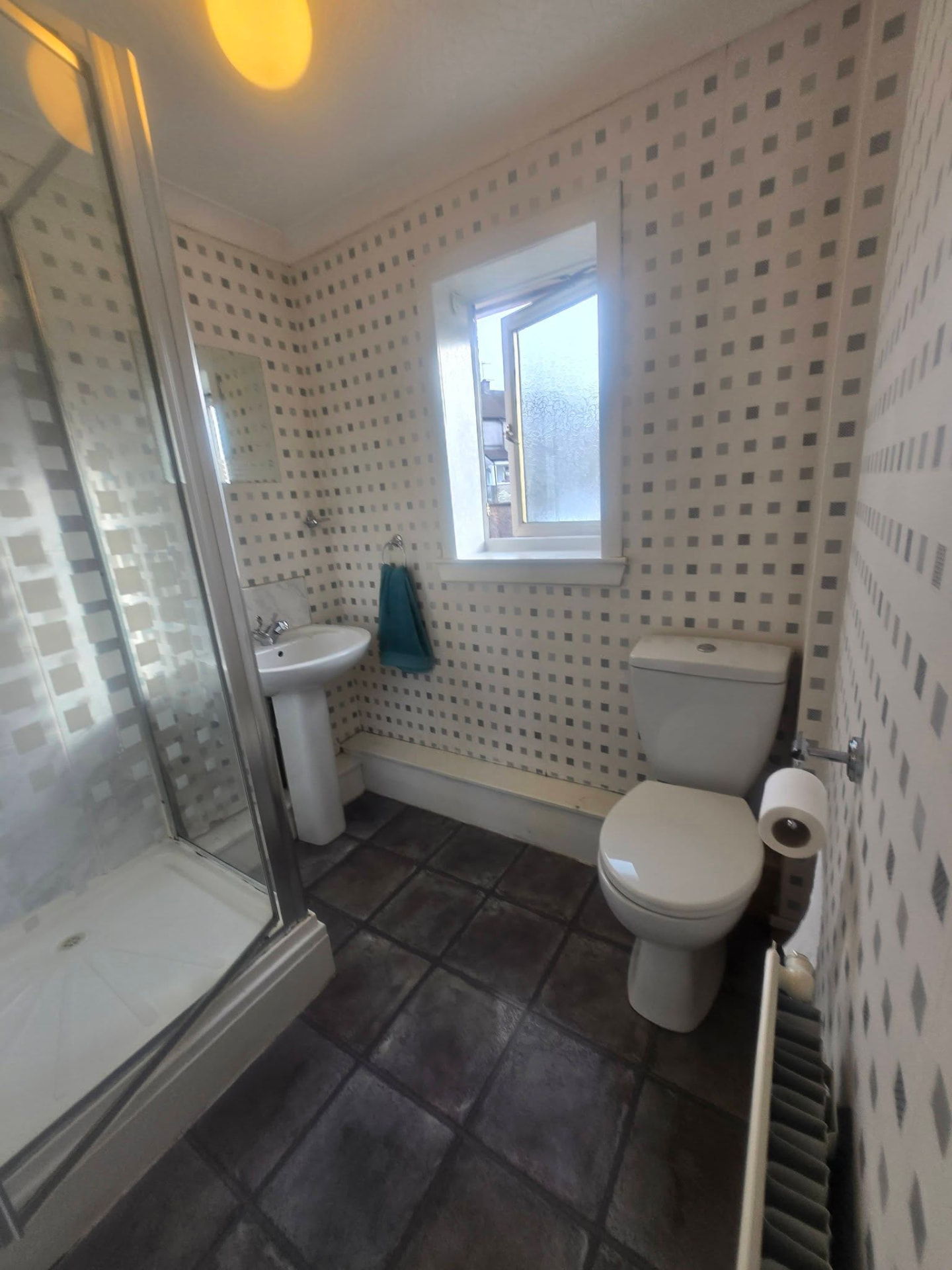Old shower room with patterned wallpaper, pedestal basin and corner shower before refit