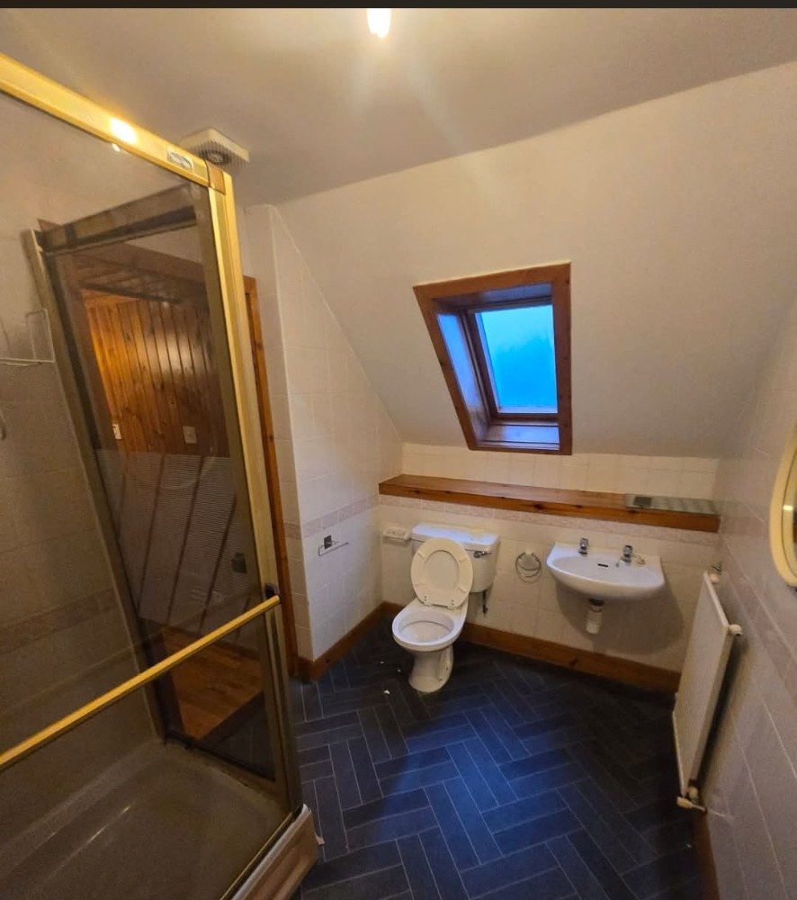 Old attic bathroom with gold-framed shower enclosure before refit