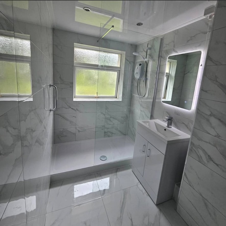 Bright marble bathroom with large shower tray and LED mirror
