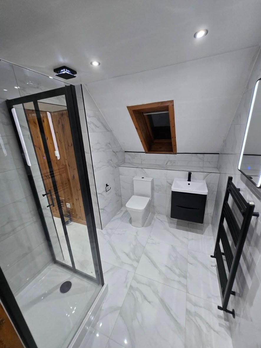 Attic bathroom after refit with marble tiling, black shower frame and wall-hung vanity